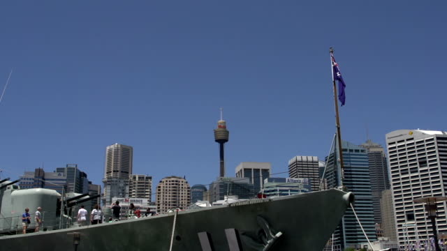 Vor-einem-großen-marine-Schiff-mit-der-Australische-Flagge-mit-den-Sydney-tower-und-die-skyline-der-Stadt-im-Hintergrund.