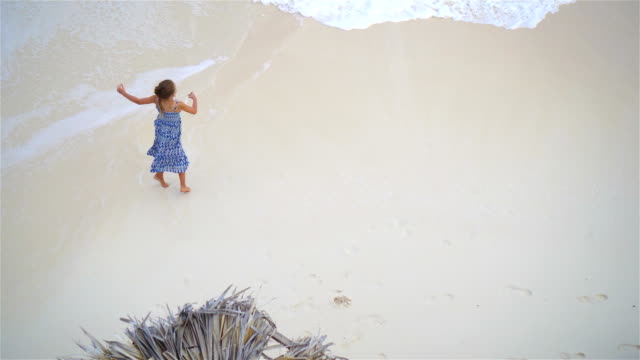 Entzückende-kleine-Mädchen-eine-Menge-Spaß-im-flachen-Wasser.-Ansicht-von-oben-an-einem-einsamen-Strand-mit-türkisblauem-Wasser