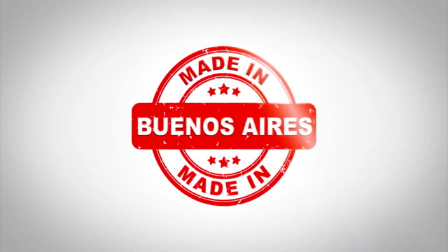 Made-In-BUENOS-AIRES-unterzeichnet,-Stanz-hölzernen-Stempel-Textanimation.-Roter-Tinte-auf-Clean-White-Paper-Oberfläche-Hintergrund-mit-grünen-matten-Hintergrund-enthalten.
