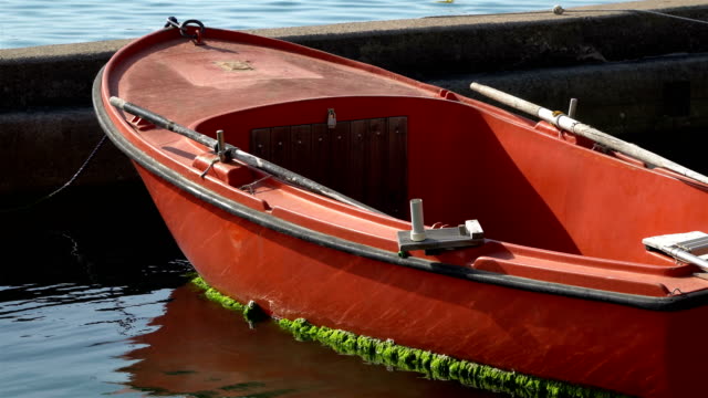 Braun-rot-Ruderboot-an-der-Küste-verankert.