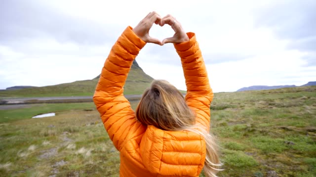 Mujer-joven-en-Islandia-que-marco-del-dedo-corazón-forma-a-la-famosa-montaña-de-Kirkjufell