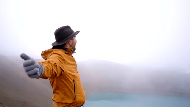 Hombre-joven-de-brazos-extendidos-en-el-espectacular-lago-de-cráter-en-Islandia