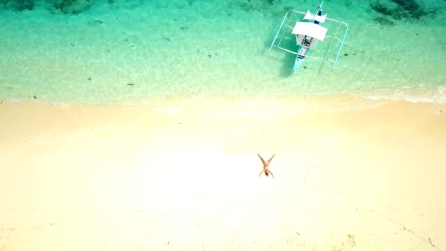 Drone-shot-aerial-view-of-young-woman-lying-down-like-star-shape-on-idyllic-tropical-beach-,-shot-in-the-Philippines