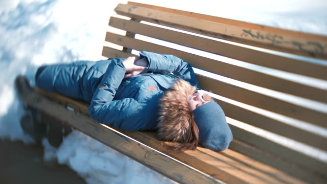 Junge-Frau-im-Park-auf-einer-Bank-im-Winter-schläft.