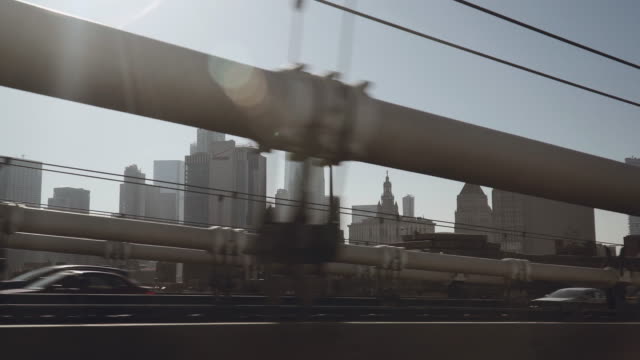 A-view-of-Lower-Manhattan-skyline-filmed-in-the-afternoon-from-the-Uber-taxi-car-driving-on-the-western-part-of-the-bridge-above-the-East-River-in-New-York,-United-States