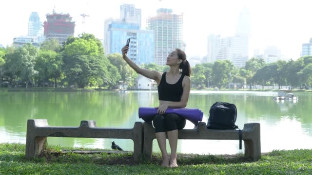 Woman-Sitting-In-Park-And-Using-Mobile-Phone