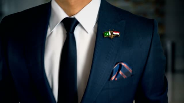 Geschäftsmann-zu-Fuß-in-Richtung-Kamera-mit-Freund-Land-Flaggen-Pin-Pakistan---Ägypten
