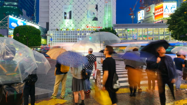 Stadtteil-Shibuya-in-der-regnerischen-Nacht-mit-Publikum-vorbeigehen-Zebrastreifen.-Tokio,-Japan.-4K-Zeitraffer.