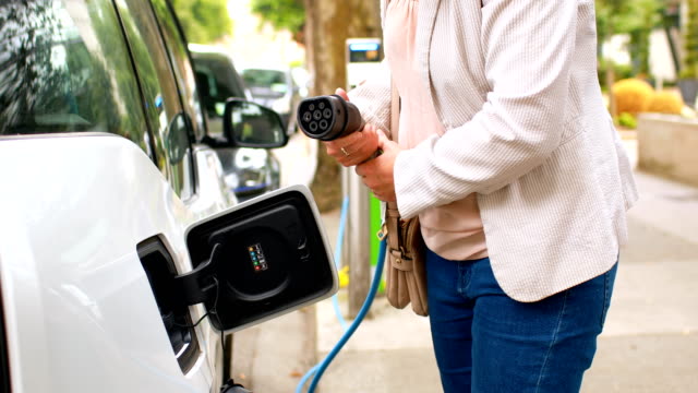 Woman-charging-electric-car-at-charging-station-4k
