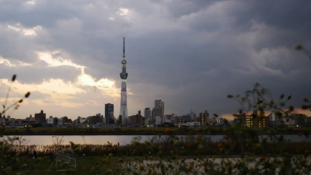 Time-lapse-view-of-Tokyo-Skytree-with-Arakawa-river-and-Tokyo-city-in-background.Tokyo-Skytree-is-a-broadcasting,-restaurant-and-observation-tower-in-Sumida-Japan.