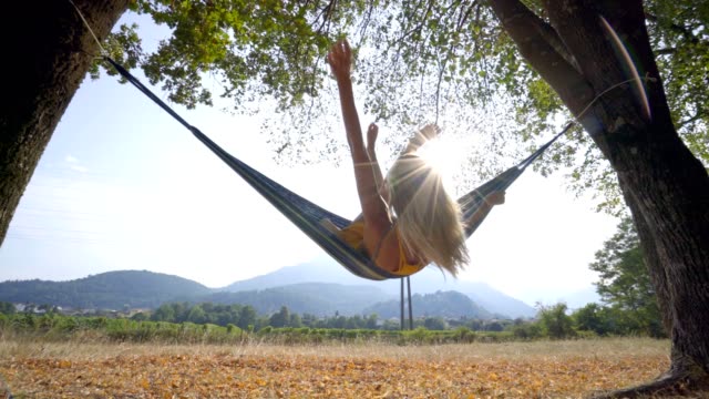 Joyful-young-woman-on-hammock-relaxing-in-Autumn--People-travel-vacations-nature-concept