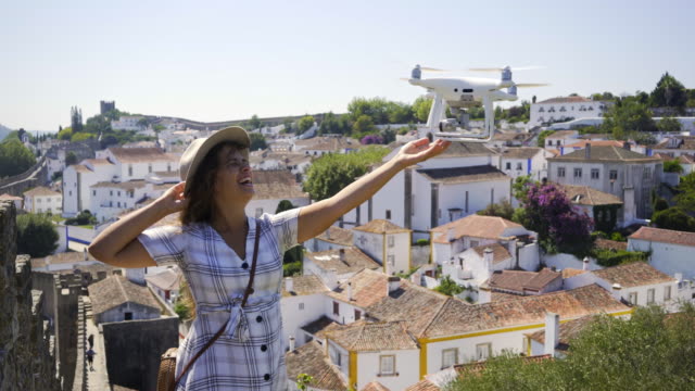 Excited-lady-touching-flying-drone-in-ancient-town