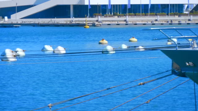 Rows-of-white-raid-barrels-are-connected-by-ropes-with-ships-and-large-yachts