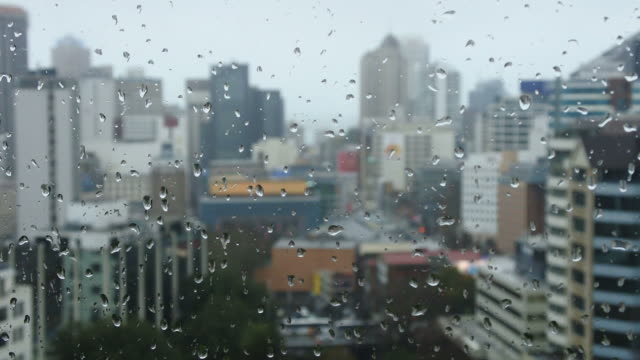 Rain-drops-falls-on-a-window-with-urban-cityscape-view