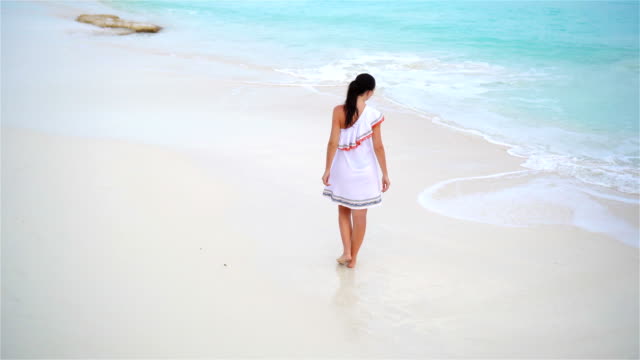 Young-beautiful-woman-on-tropical-seashore.-Back-view-of-young-girl-in-beautiful-dress-background-the-sea