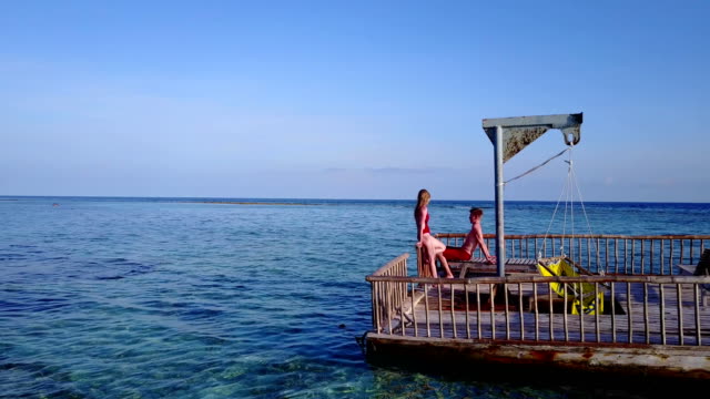 v03833-fliegenden-Drohne-Luftaufnahme-der-Malediven-weißen-Sandstrand-2-Personen-junges-Paar-Mann-Frau-entspannend-auf-sonnigen-tropischen-Inselparadies-mit-Aqua-blau-Himmel-Meer-Wasser-Ozean-4k-schwimmenden-Ponton-Steg-Sonnenbaden-zusammen