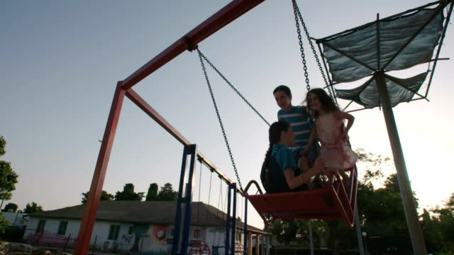 Niños-que-hace-pivotar-juntos-en-un-parque-infantil-público