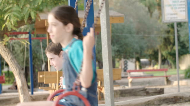 Niños-que-hace-pivotar-juntos-en-un-parque-infantil-público