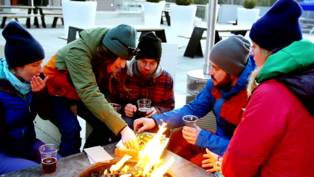 Friends-having-snacks-near-campfire