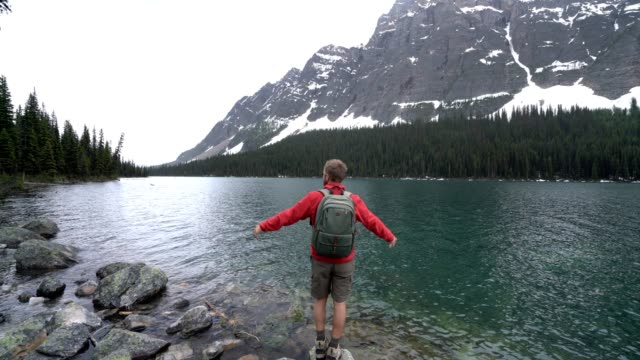 Excursionista-celebrando-por-lago-de-montaña,-4K