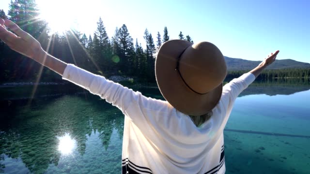 Woman-arms-outreached-by-alpine-lake-in-the-Canadians-rockies