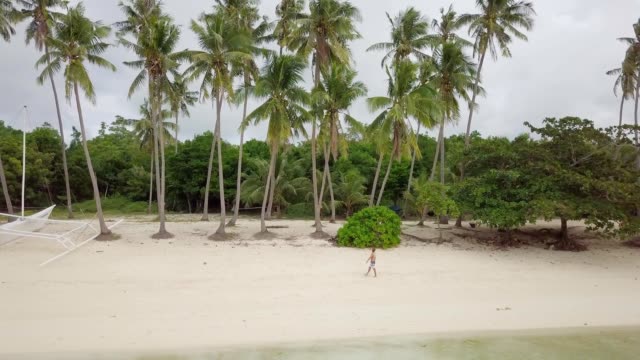 Drone-shot-aerial-view-of-young-man-relaxing-on-tropical-beach,-contemplating-nature.-4K-resolution-video.-People-travel-vacations-concept.-Shot-in-the-Philippines,-Asia
