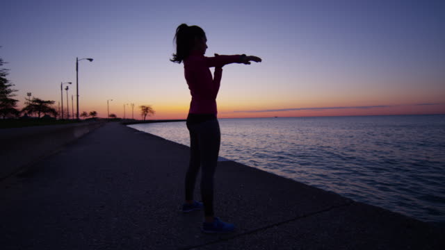 Hispanic-Caucasian-female-silhouette-stretching-in-Chicago-sunset