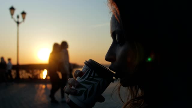 Frau-trinkt-Kaffee-in-einem-Kai-in-Sonnenuntergangszeit,-Nahaufnahme-des-Gesichts