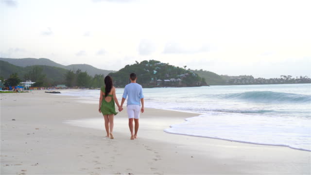 Young-couple-on-white-beach-during-summer-vacation.-Happy-family-enjoy-their-honeymoon