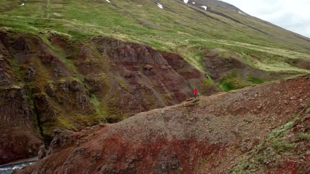Amazing-drone-point-of-view-of-man-hiking-on-mountain-ridge-over-canyon-in-Iceland