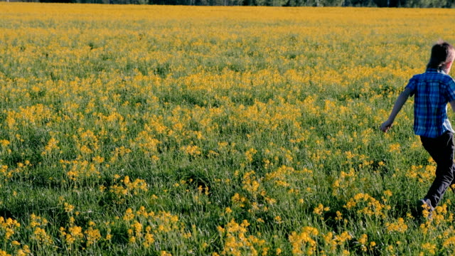 Niño-corre-en-el-campo-entre-las-flores-amarillas.