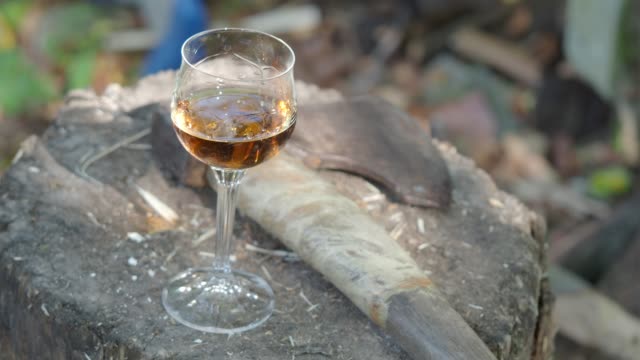 glass-of-cognac-and-an-ax-on-a-wooden-deck
