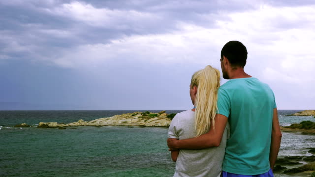 Pareja,-abrazar,-mirar-el-mar-tempestuoso,-Grecia