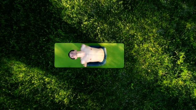 Slender-young-man-practicing-yoga-in-park.-Top-view.-Copter-footage.