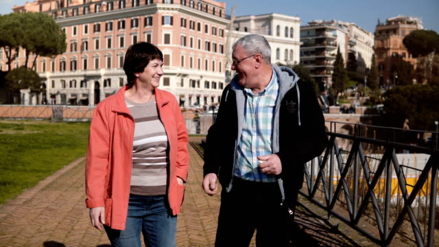 Happy-romantic-senior-Caucasian-couple-walking-together-smiling-and-talking-on-vacation-to-beautiful-autumn-Rome,-Italy.