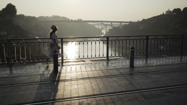 Lady-in-hat-and-dress-walking-on-bridge
