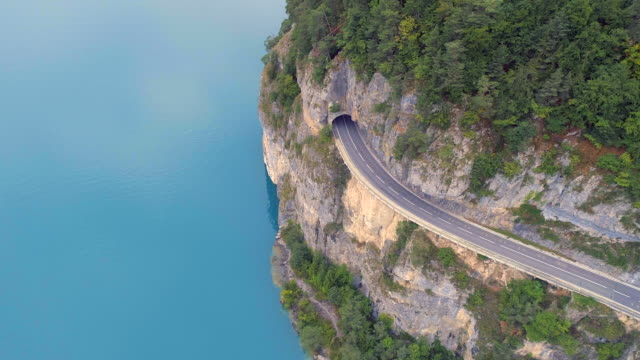 Carretera-de-montaña-con-lago-azul-abajo-y-túnel