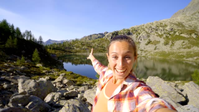 Junge-Frau-nehmen-Selfie-am-Bergsee.-Junge-Frau-in-den-Schweizer-Alpen-wandern-nimmt-video-Selfies-Baby-den-herrlichen-Alpensee