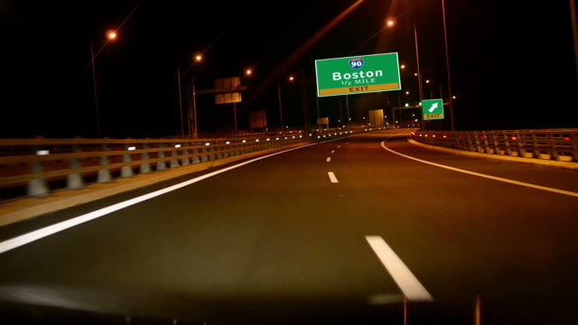 Por-la-carretera/la-autopista-en-la-noche,-tome-la-salida-en-la-señal-de-la-ciudad-de-Boston,-Massachussets