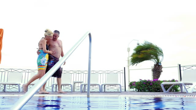 Eine-ältere-paar-Hände-halten-und-Fuß-neben-dem-resort-pool