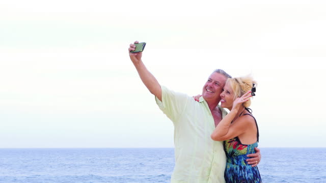 An-older-couple-having-fun-and-taking-selfies-on-the-beach