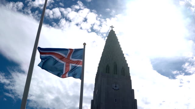 Hermosa-vista-de-la-preciosa-iglesia-de-Hallgrímskirkja-en-Reykjavik,-Islandia-y-la-bandera-nacional-ondeando-en-el-viento