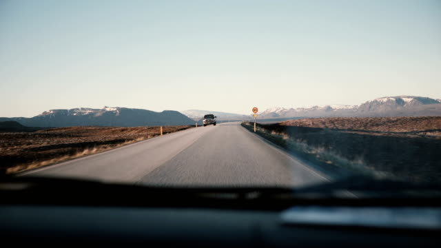 View-inside-the-car-through-the-windshield-on-beautiful-countryside-road-with-beautiful-sunset,-mountains-landscape