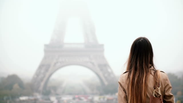 Atractiva-joven-caminando-sola-en-el-centro,-visitar-la-Torre-Eiffel-a-niebla-por-la-mañana-en-París,-Francia