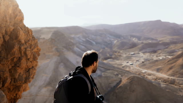 Man-takes-photos-of-amazing-desert-landscape.-European-male-tourist-with-camera-at-massive-mountain-view.-Israel-4K
