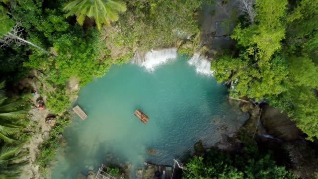Drone-shot-aerial-view-of-young-woman-bamboo-rafting-at-tropical-waterfall.-4K-resolution-video,-shot-in-the-Philippines.-People-travel-fun-vacations-adventure-concept