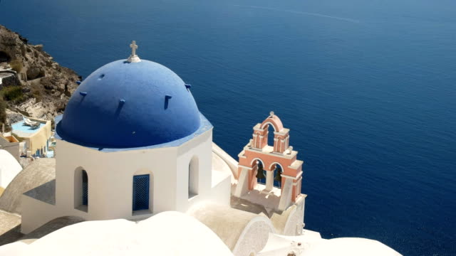 blue-church-dome,-pink-arch-and-bells-in-oia,-santorini