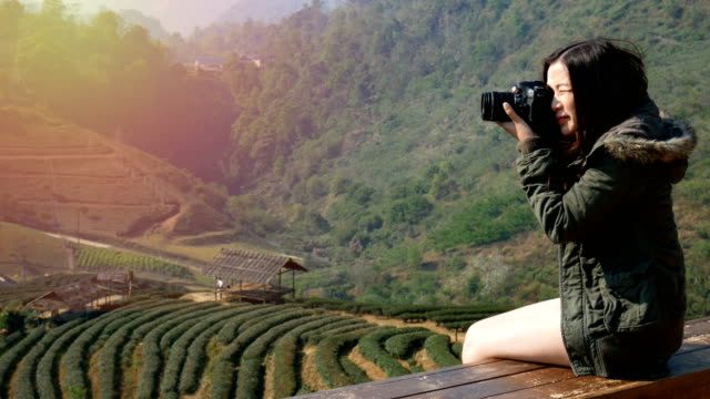 4K-Aufnahmen-von-glücklich-asiatische-Touristen-Frau-nehmen-Foto-von-der-schönen-Natur-von-Feld-Teeplantage-in-Asien-mit-Digitalkamera-bei-Sonnenaufgang.-Reisen-und-Urlaub-Konzept