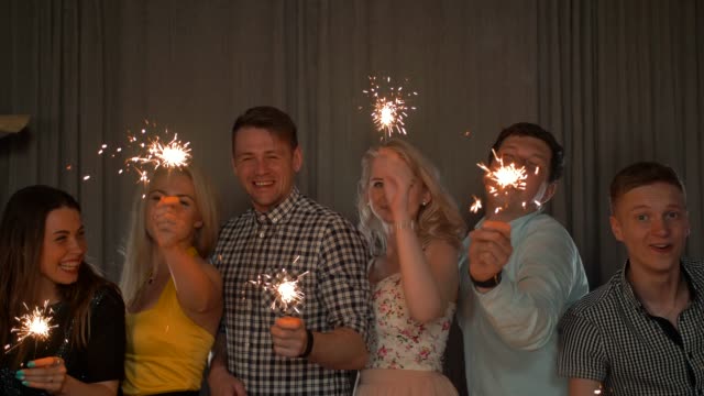 Group-of-cheerful-young-people-carrying-sparklers