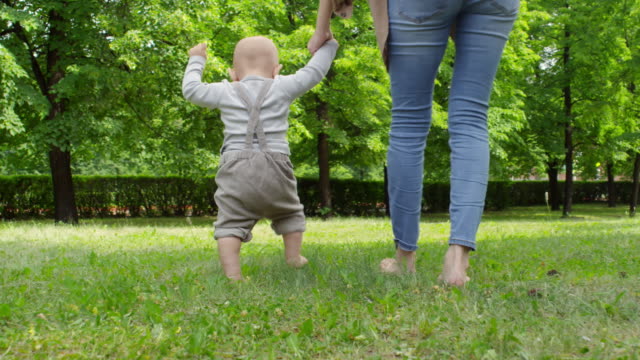 Mother-and-Baby-Boy-Walking-Barefoot-on-Grass